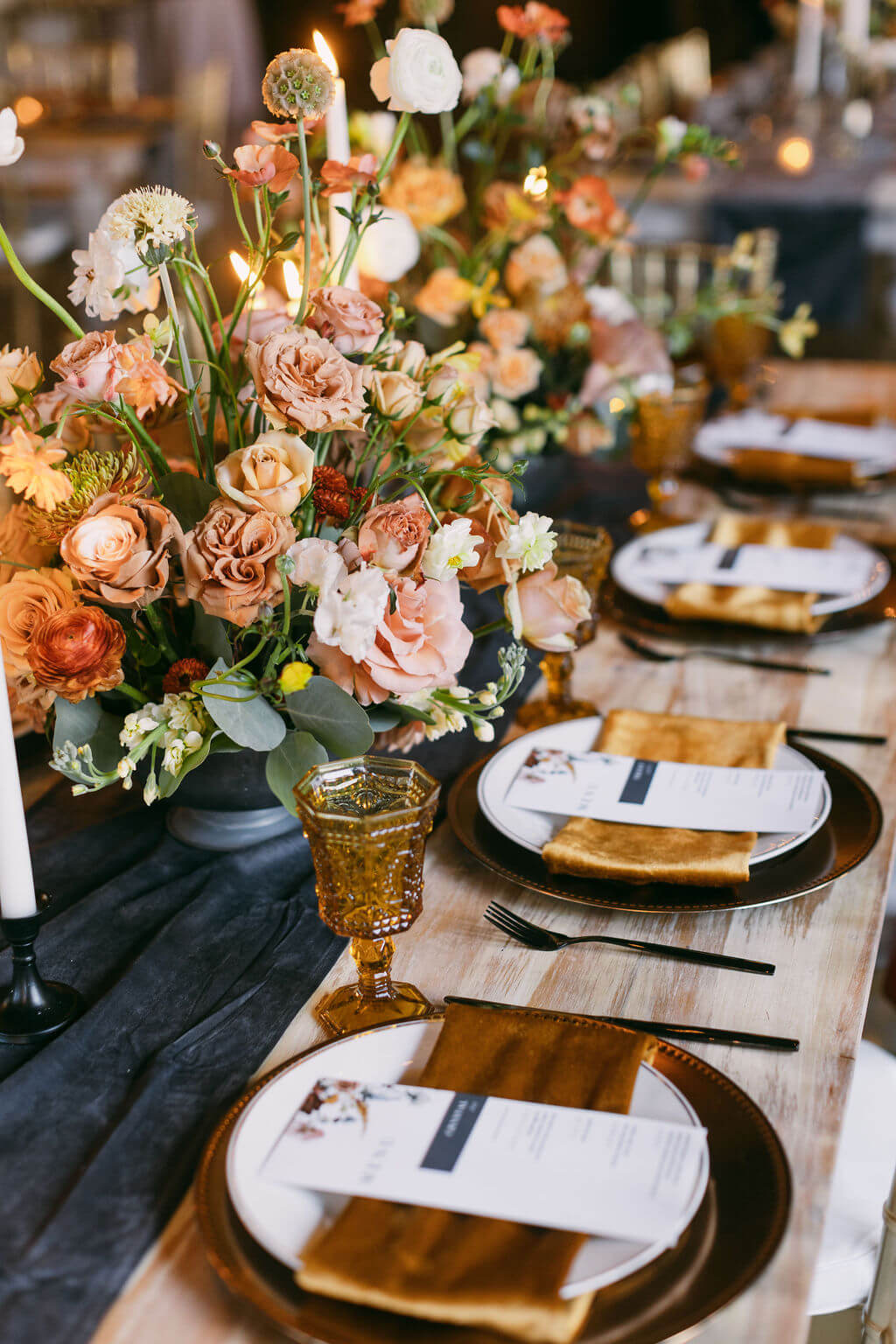 a beautifully arranged table set with orange and white flowers in the middle of the table